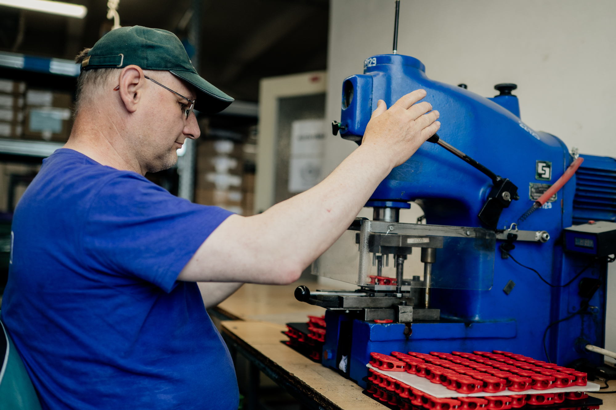 Pracovník SOLEA obsluhuje poloautomatické montážní zařízení při kompletaci plastových dílů.