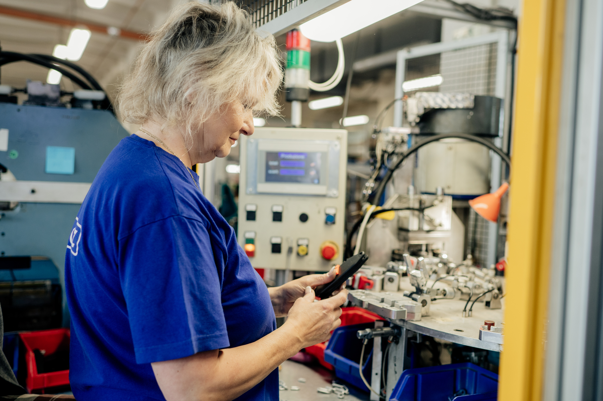 Pracovnice SOLEA kontroluje díly na strojním montážním pracovišti s poloautomatickou linkou.